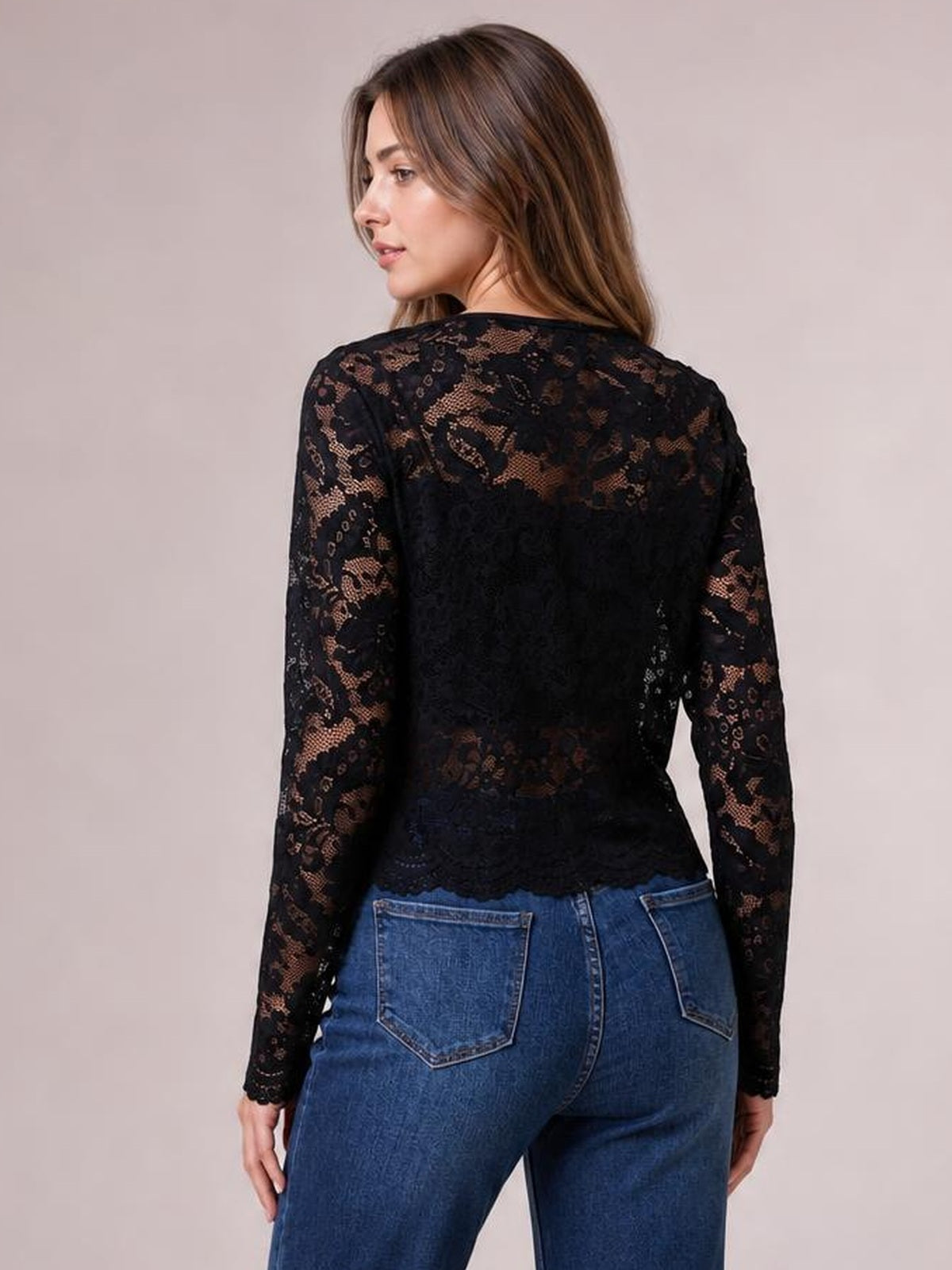 Model shown from the back wears a black lace open-front long-sleeve jacket with a fitted silhouette and scalloped hem over blue jeans.
