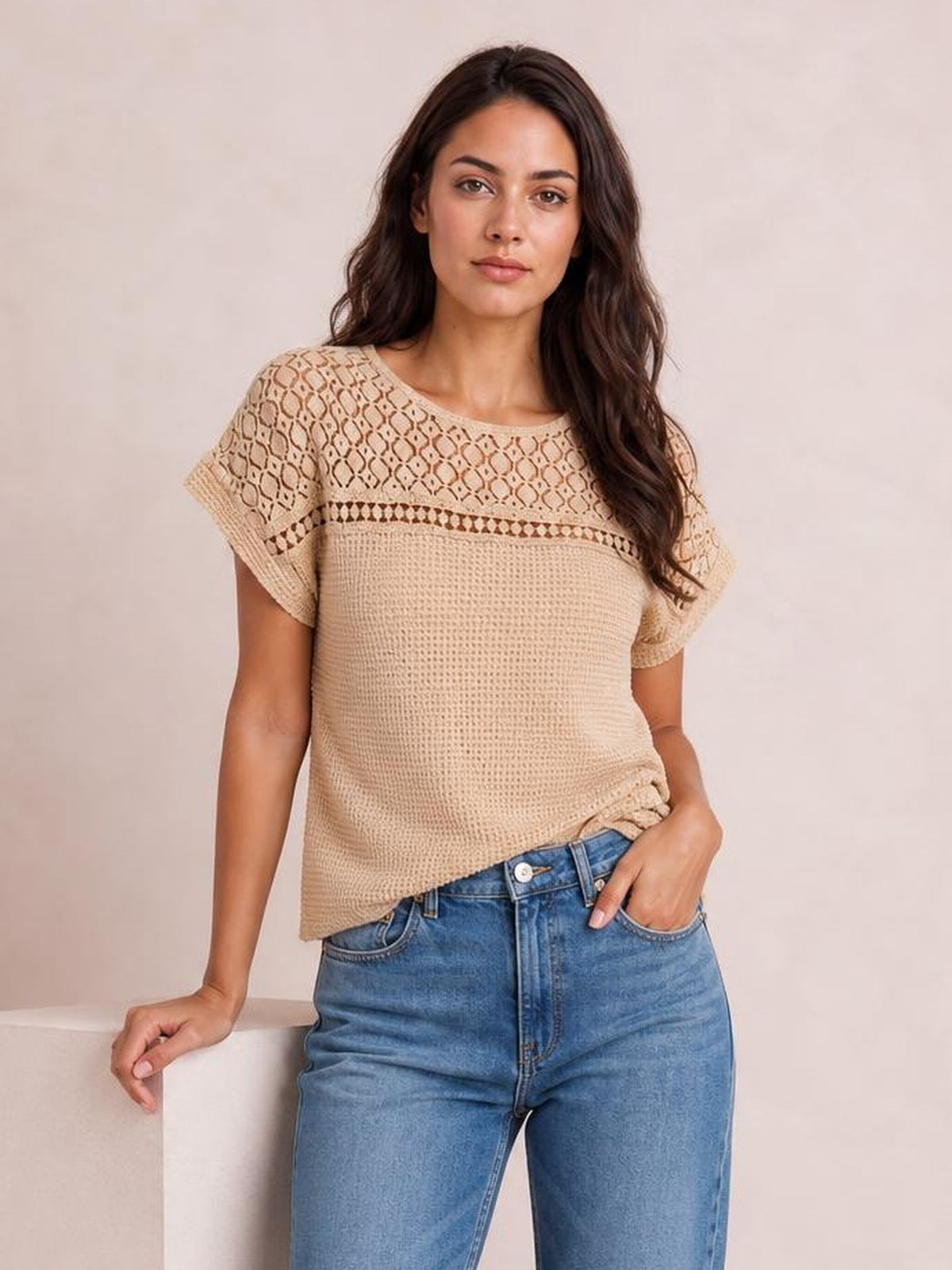 A model poses in a beige lace patchwork waffle knit top with short sleeves, a round neckline, textured construction, and a relaxed straight silhouette.