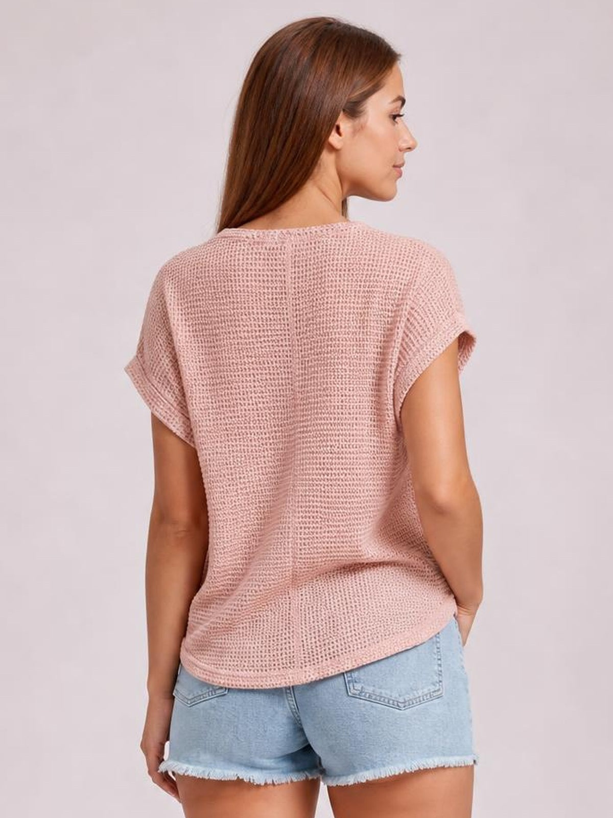 Model shown from the back in a dusty pink waffle knit top with short sleeves, a relaxed straight silhouette, and a gently curved hem.