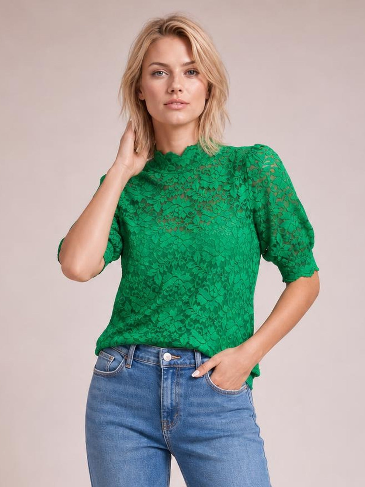 Model poses in a bright green lace top with a scalloped mock neck, short puff sleeves, and a regular-fit silhouette.