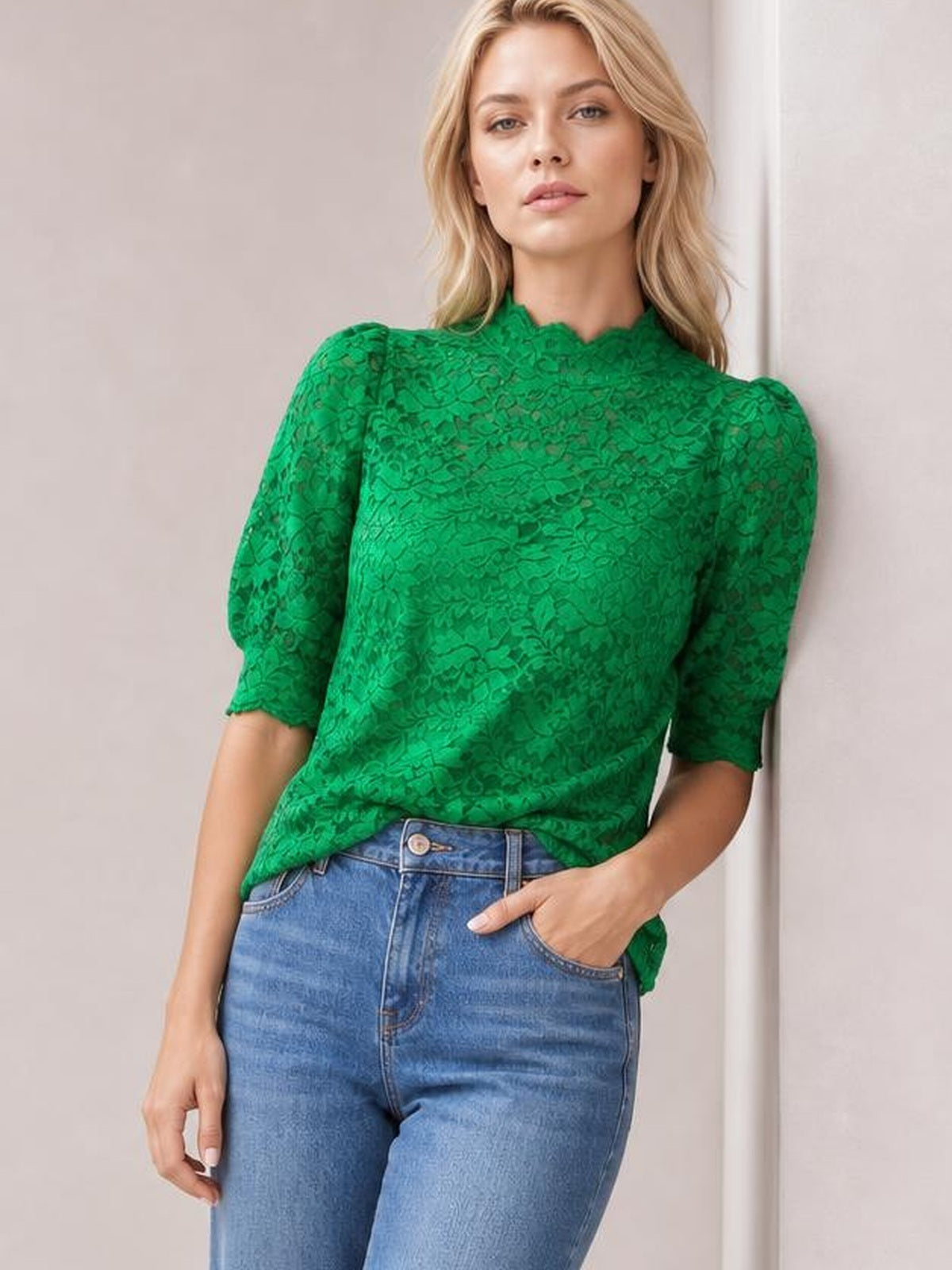 A model poses in a vibrant green lace top with a scalloped mock neck, short puff sleeves, regular silhouette, and scalloped sleeve edges.
