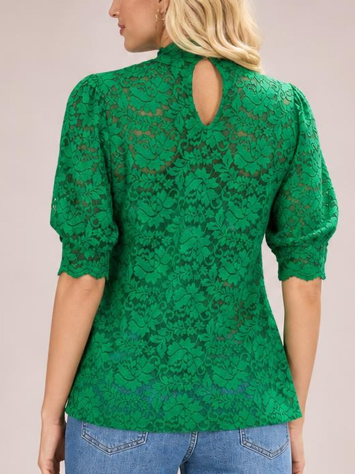 A back-facing model wears a green lace top with a mock neck, keyhole opening, short puff sleeves, scalloped cuffs, and a regular silhouette.