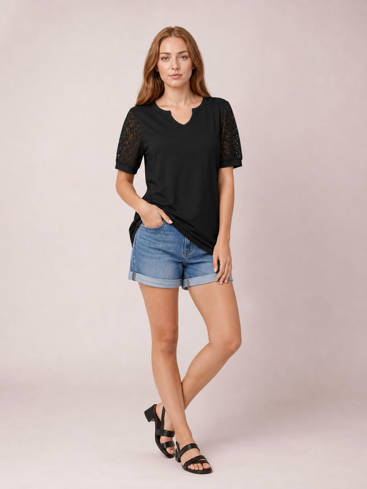 Model wears a black Lace Short Sleeve T-Shirt with semi-sheer openwork lace sleeves, a notched neckline, relaxed silhouette, and crossed-leg pose.