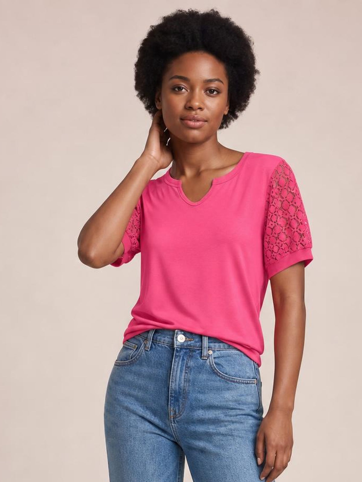 Model poses in a bright pink lace short sleeve T-shirt with a relaxed silhouette, V-notch neckline, rolled cuffs, and semi-sheer openwork sleeves.