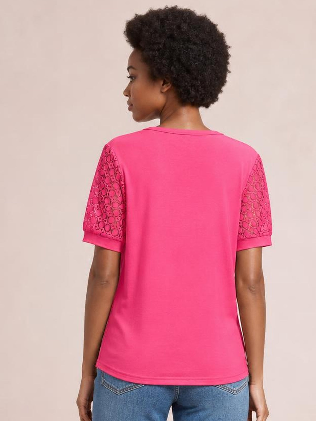 A model viewed from the back wears a bright pink short sleeve T-shirt with semi-sheer lace openwork sleeves, crew neckline, and relaxed straight silhouette.