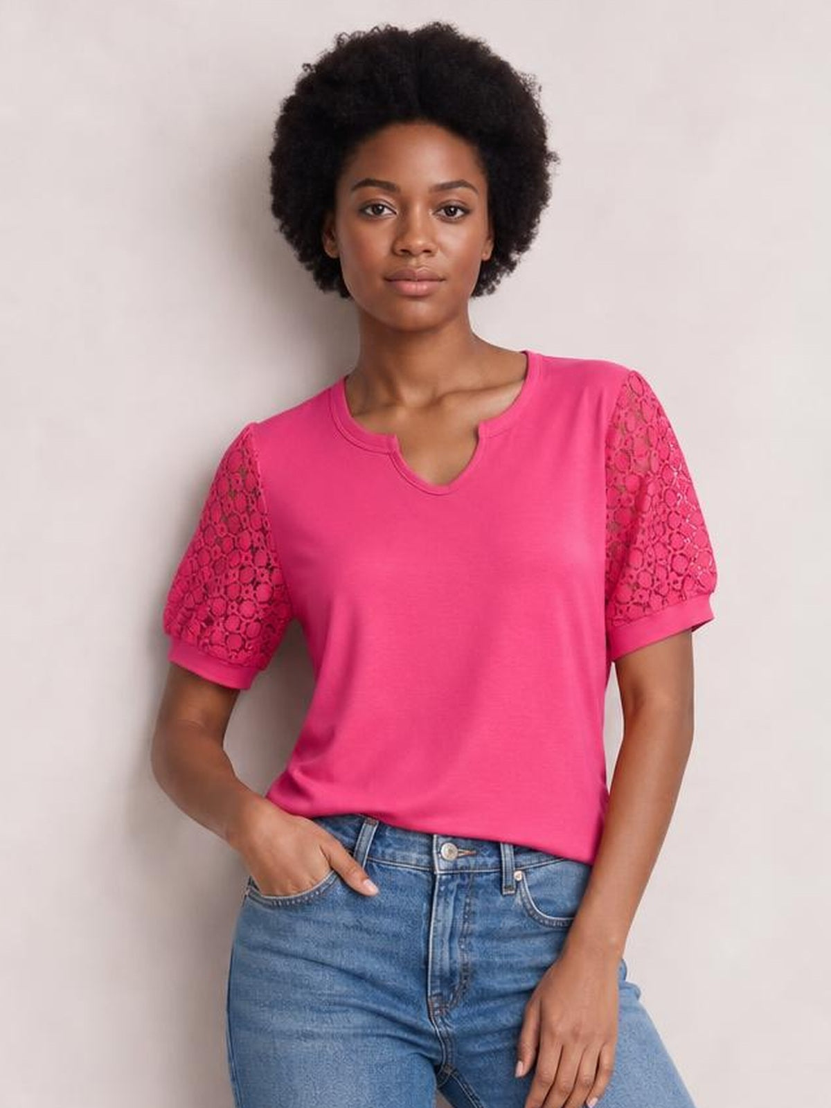 Model wears a bright pink lace short sleeve T-shirt with semi-sheer openwork sleeves, a V-notch neckline, and a relaxed straight silhouette, posing with one hand in her jeans pocket.