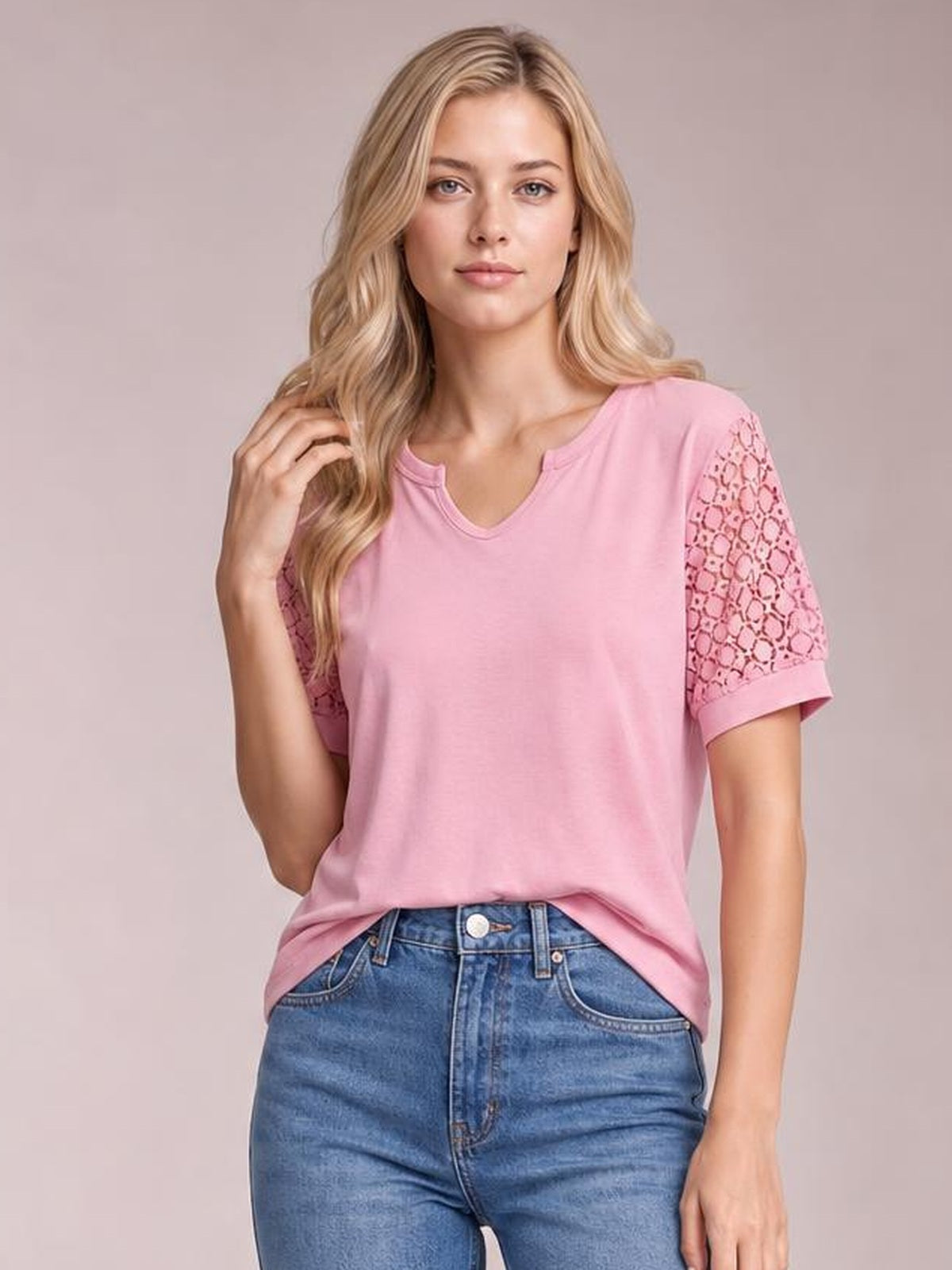 Model poses in a pink lace short sleeve T-shirt with openwork sleeves, a notched neckline, relaxed silhouette, and slight stretch.
