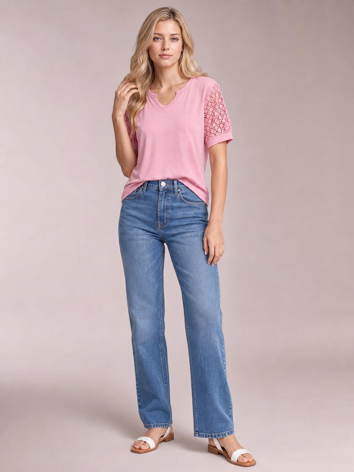 A model poses in a pink lace short sleeve T-shirt with a V-neck, relaxed silhouette, and openwork sheer sleeves.