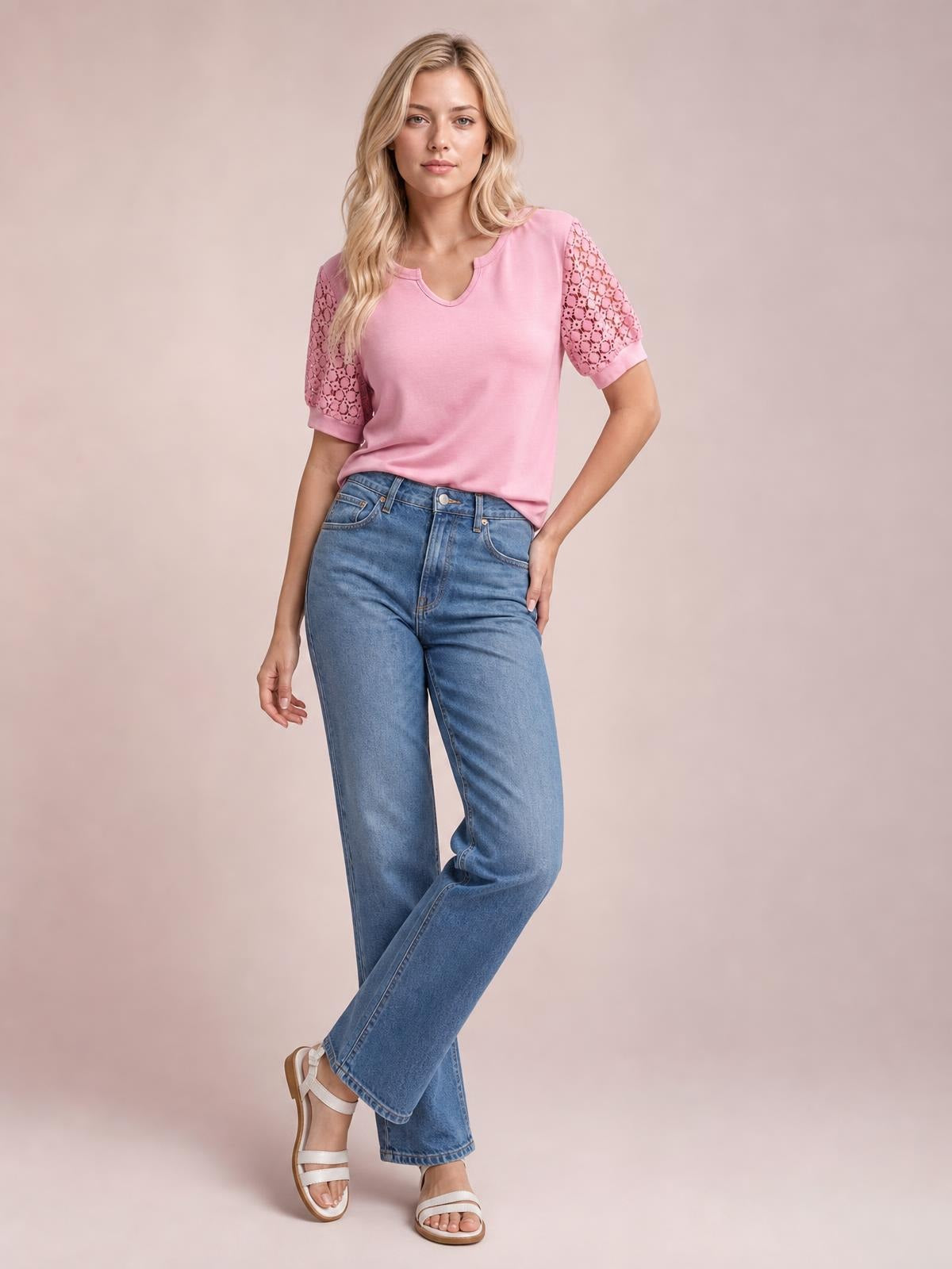 A model poses in a pink lace short sleeve T-shirt with openwork sleeves, a V-neckline, and an easy straight silhouette, one hand on her hip.