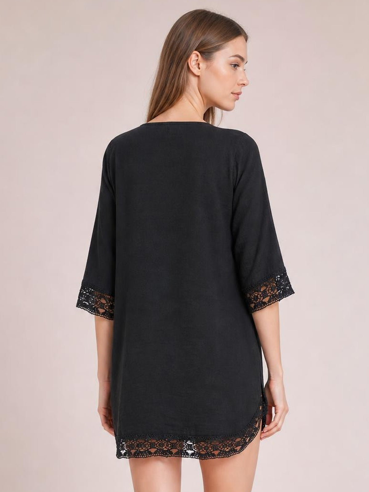 Model shown from the back wears a black cover-up with a loose straight silhouette, three-quarter sleeves, and delicate lace trim at the cuffs and hem.