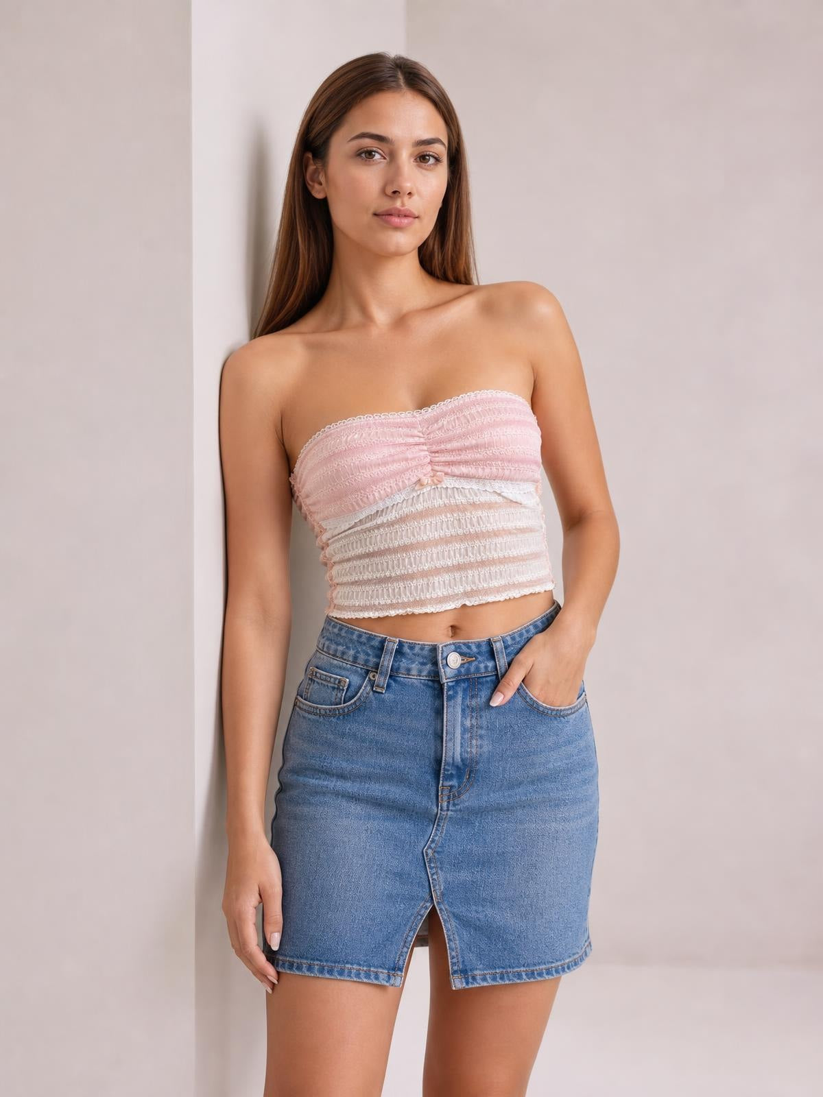 Model wearing a pink and white lace tube top with a ruched, slightly stretchy cropped silhouette and a straight strapless neckline.