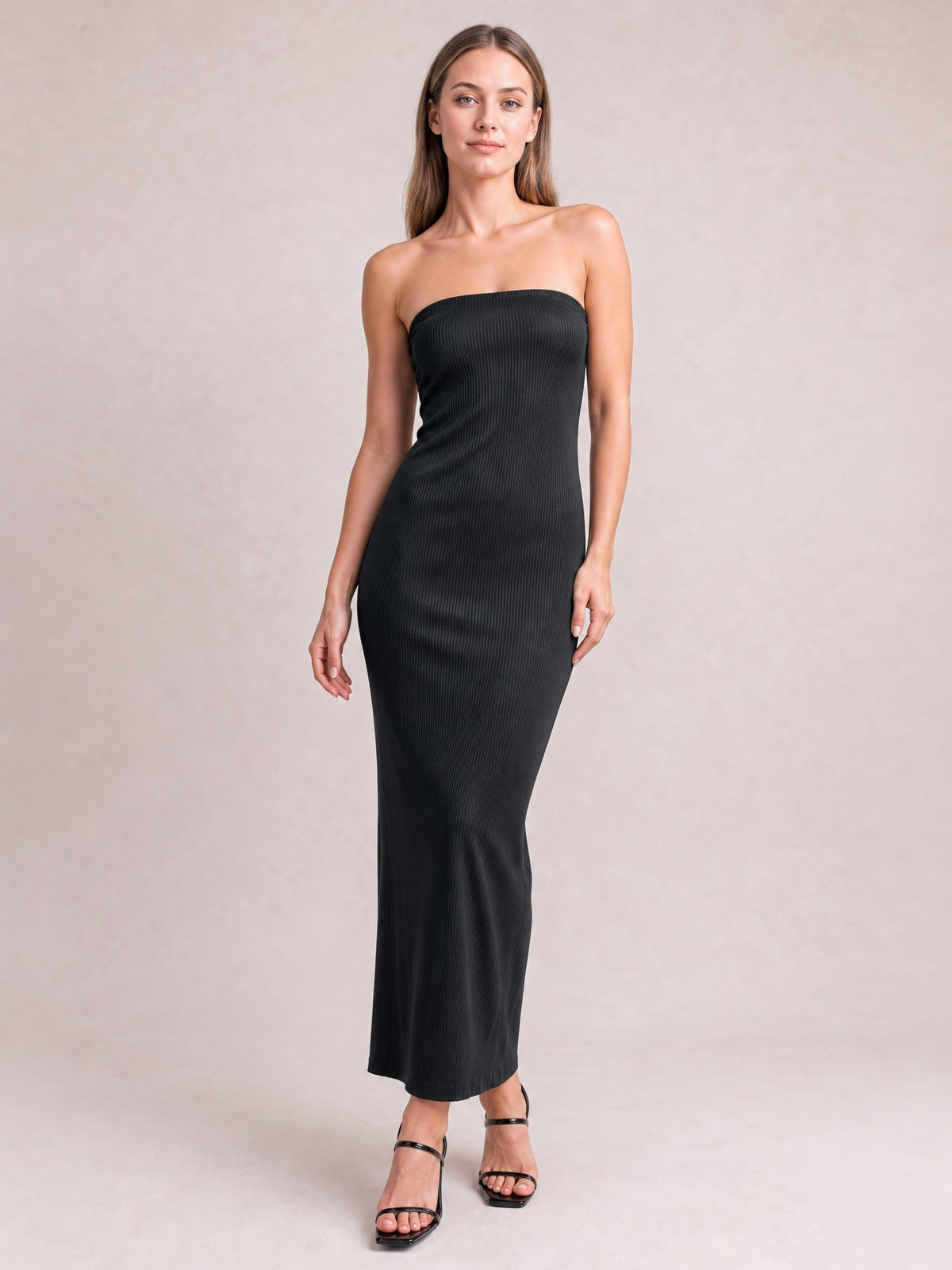 Model poses in a black strapless tube maxi dress with a body-skimming column silhouette, subtle ribbed texture, and ankle-length hem.