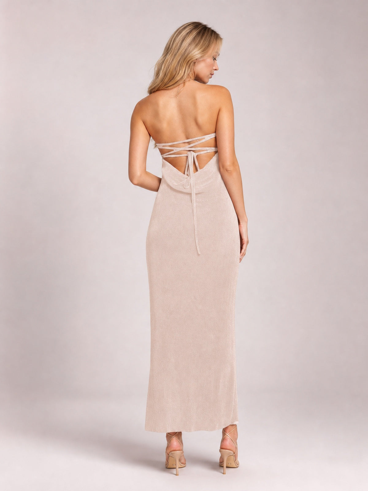Model looks over her shoulder in a blush pink Lace-Up Back Tube Maxi Dress with a slim, floor-length silhouette and strappy open back.