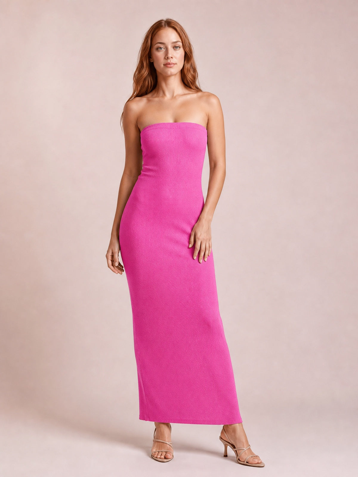 Model wears a bright pink ribbed tube maxi dress with a strapless neckline, body-skimming column silhouette, and a relaxed pose with one leg angled.