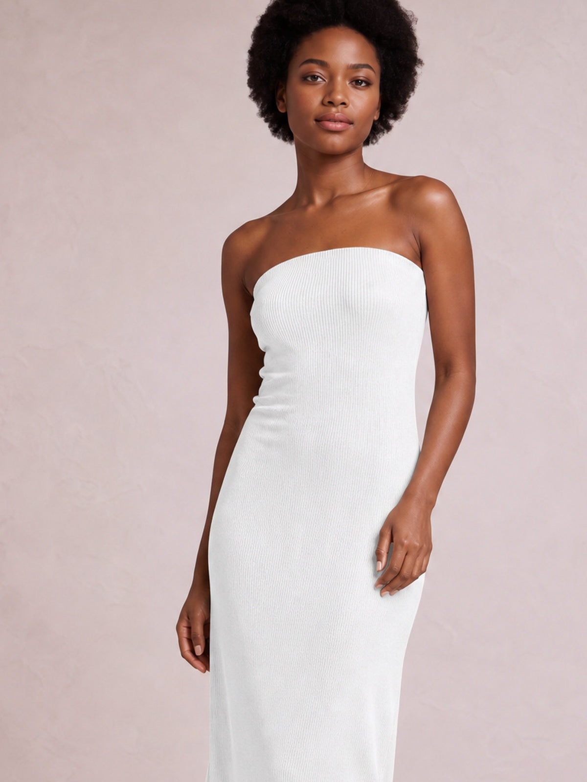 A model stands in a white strapless tube maxi dress with a body-skimming column silhouette, softly gathered sides, and a subtly textured construction.