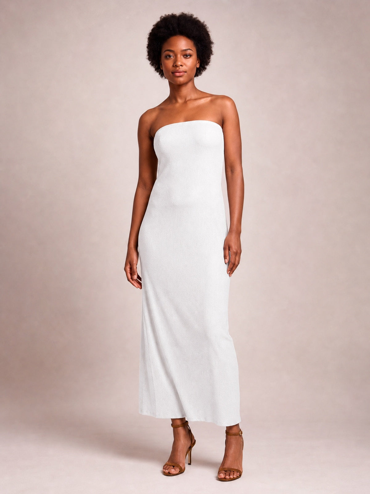 A model stands in a white strapless tube maxi dress with a body-skimming column silhouette, straight neckline, and softly fluid floor-length construction.