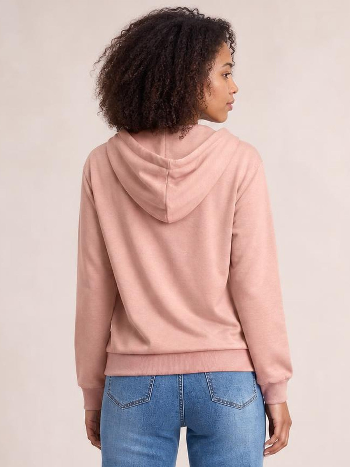 Model shown from the back wearing a blush pink long sleeve hoodie with a draped hood, ribbed cuffs and hem, and a relaxed silhouette.