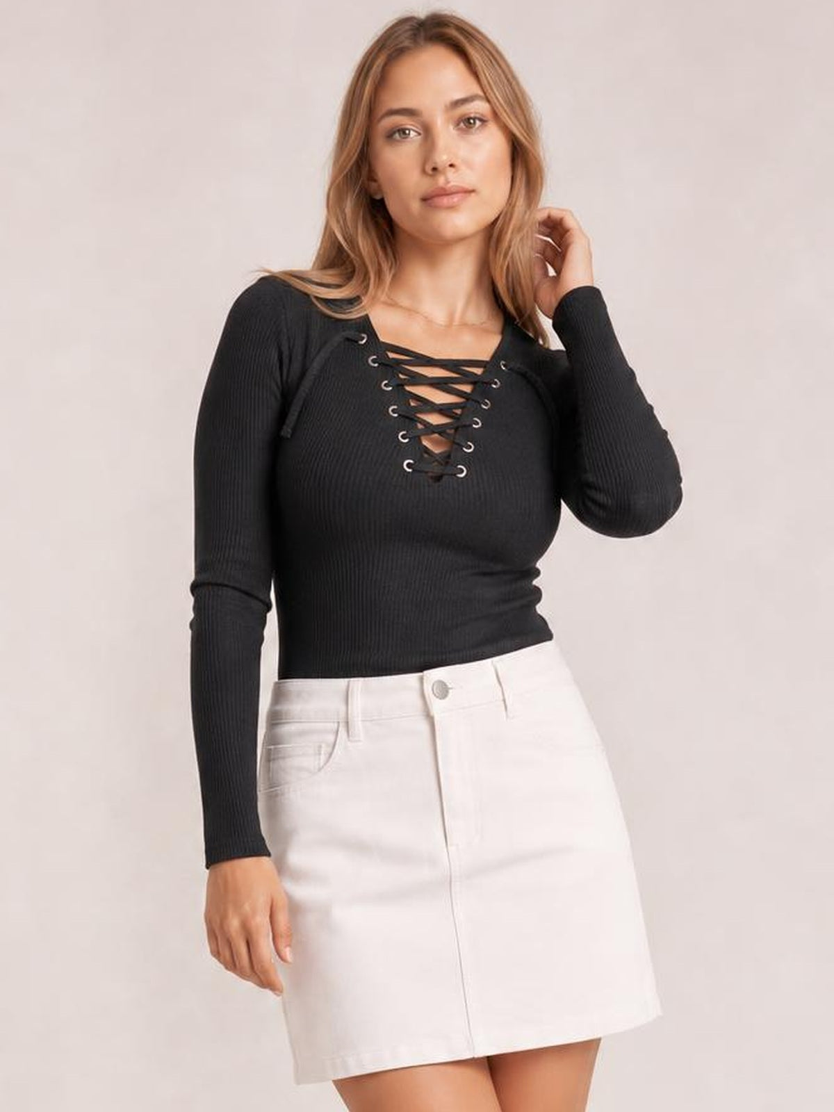Model wears a fitted black ribbed lace-up long sleeve T-shirt with crisscross chest detailing and a slightly stretchy silhouette.
