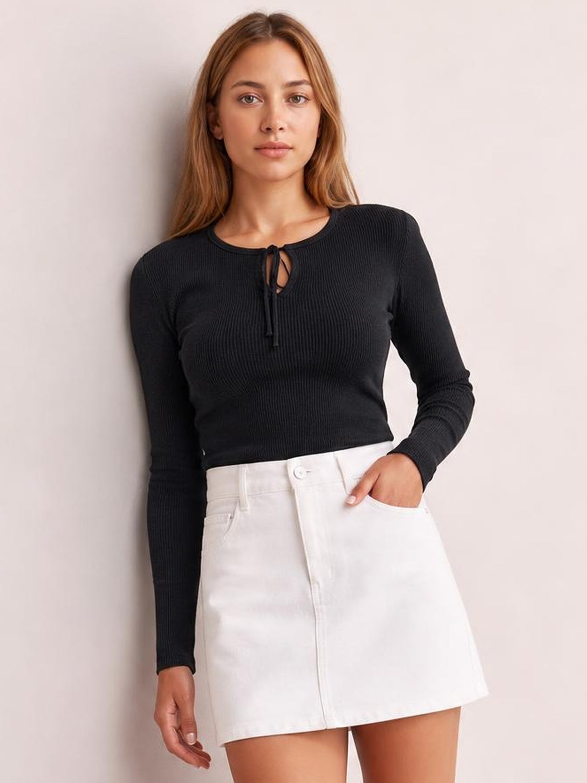 Model poses in a fitted black ribbed lace-up long sleeve T-shirt with a crisscross neckline and slightly stretchy silhouette.