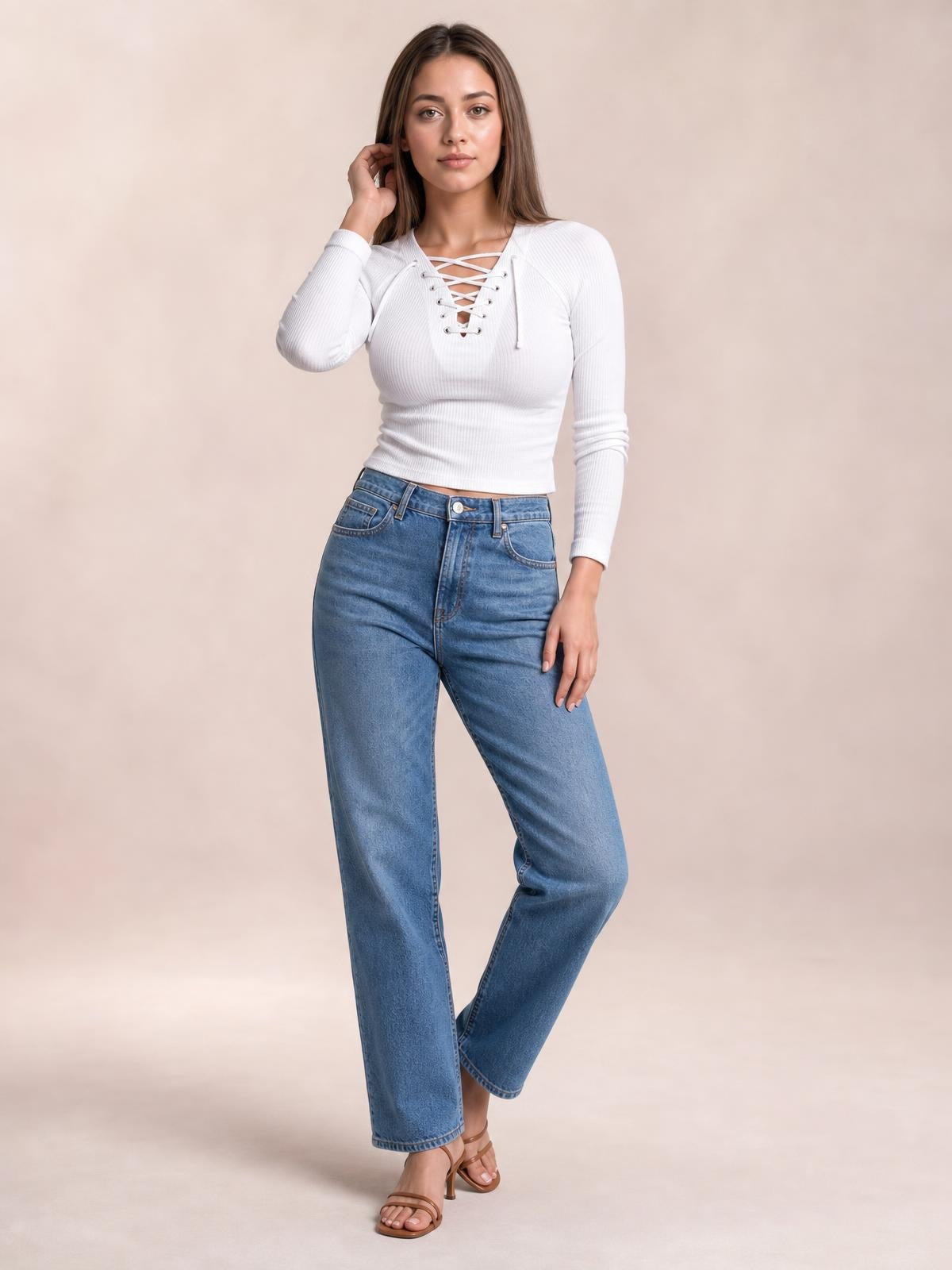 Model poses in a fitted white ribbed long sleeve T-shirt with an edgy crisscross lace-up neckline and cropped silhouette.