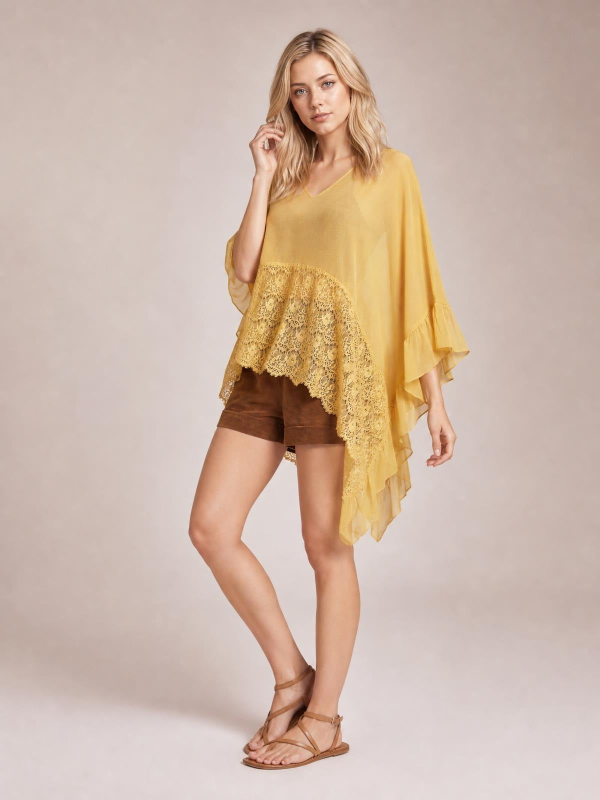 Model poses in a mustard-yellow lace V-neck cover-up with ruffled long sleeves, a flowing poncho silhouette, and an asymmetrical lace-trimmed hem.
