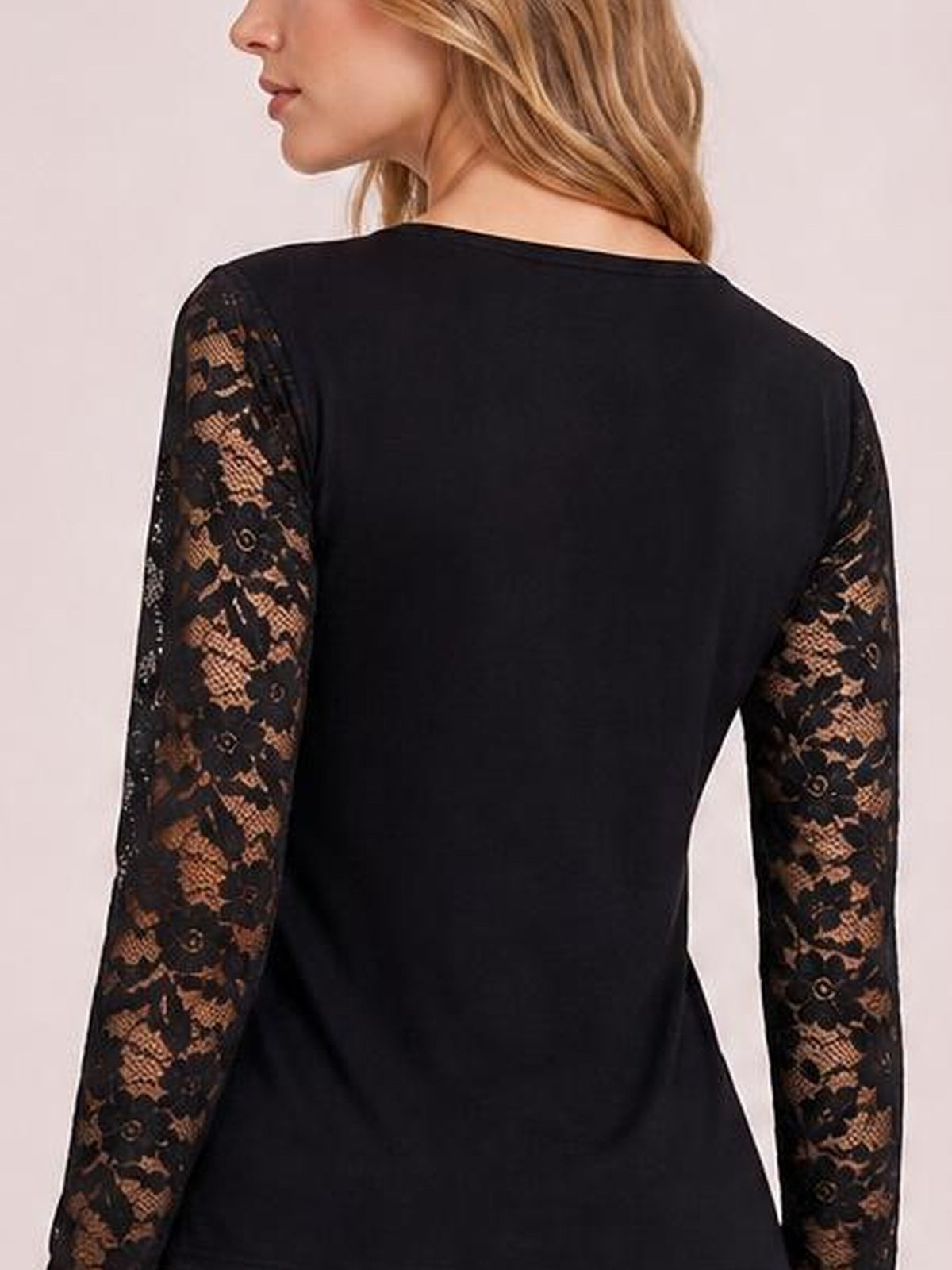 Model shown from the back in a fitted black lace long sleeve top with semi-sheer floral sleeves and a smooth, streamlined silhouette.