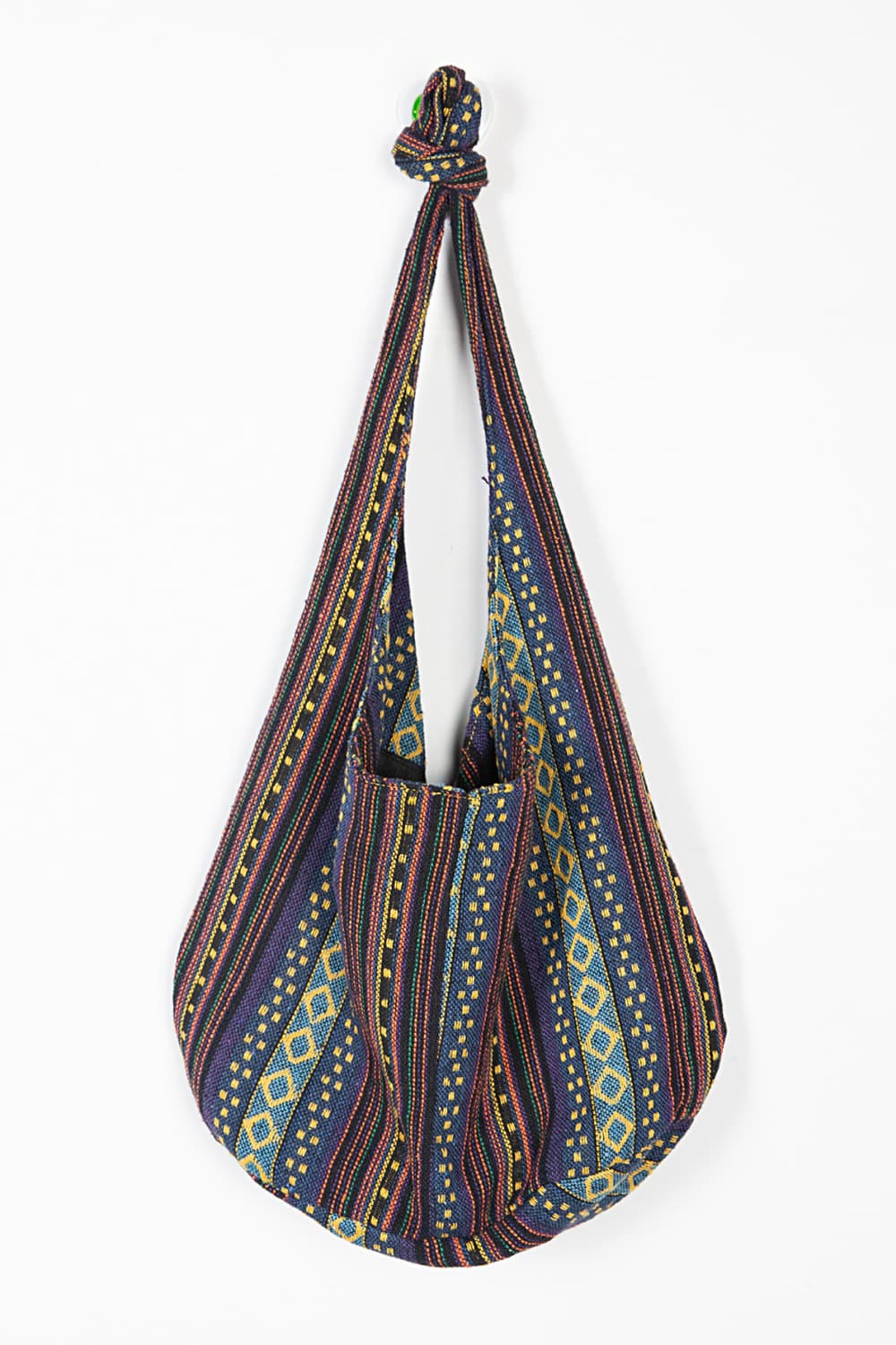 Large canvas crossbody bag with multicolored geometric stripes, a softly rounded slouchy silhouette, and an elongated strap gathered into a top knot.