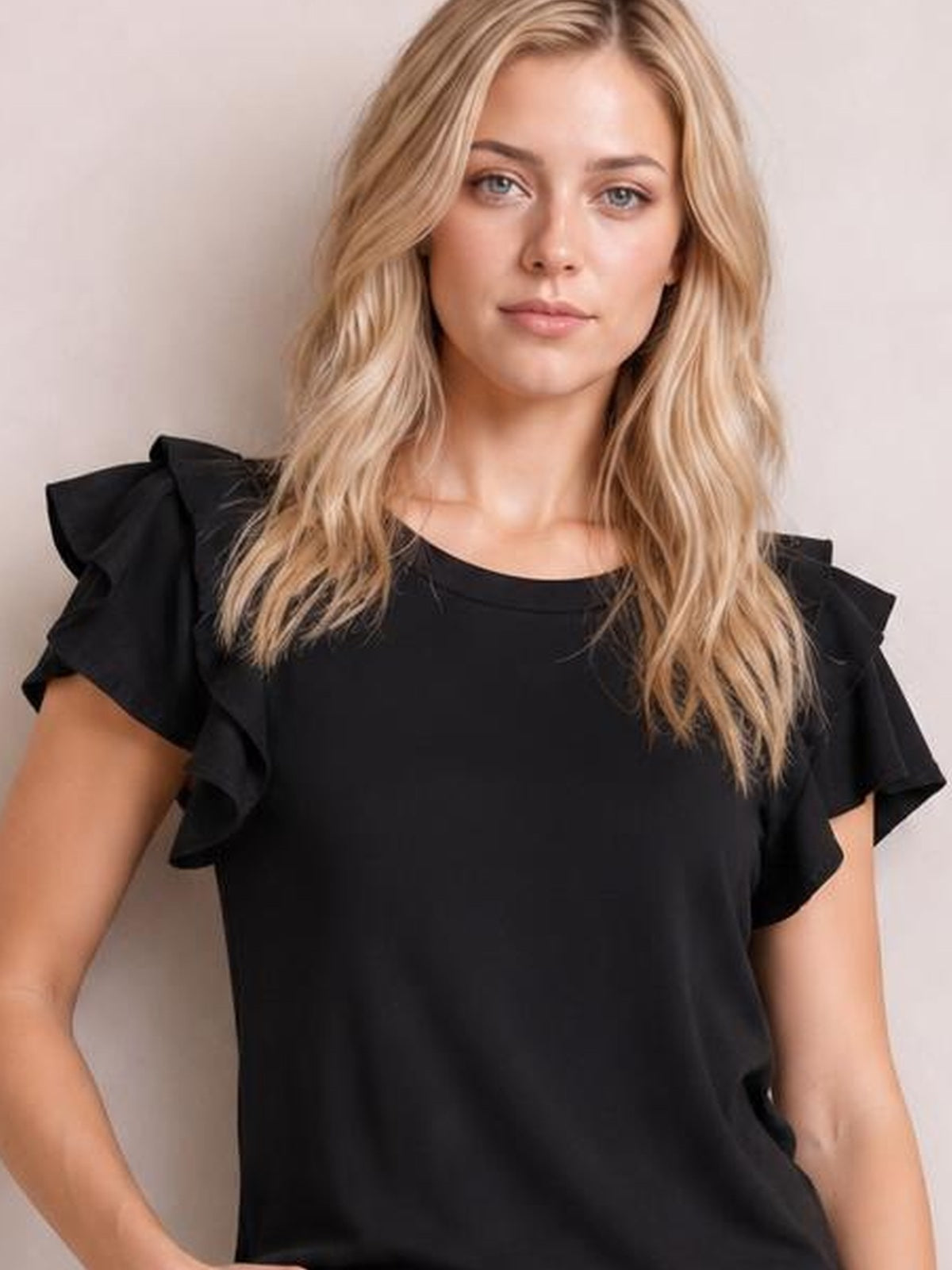 Model wearing a solid black layered flutter sleeve round neck top with short raglan sleeves and a relaxed regular-length silhouette.