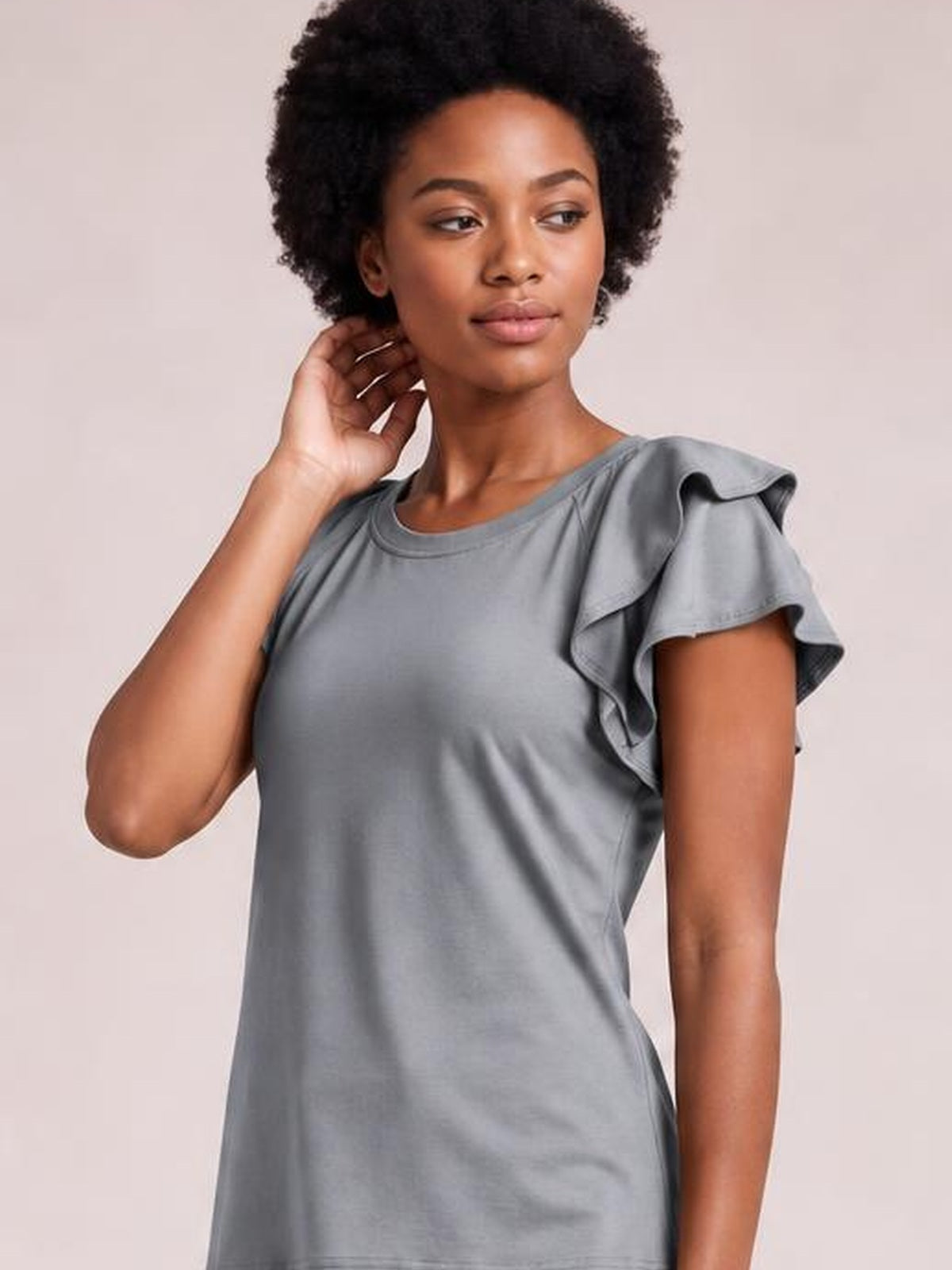 A model poses with one hand near her neck wearing a solid gray layered top with a round neckline, flutter short sleeves, and a relaxed regular silhouette.