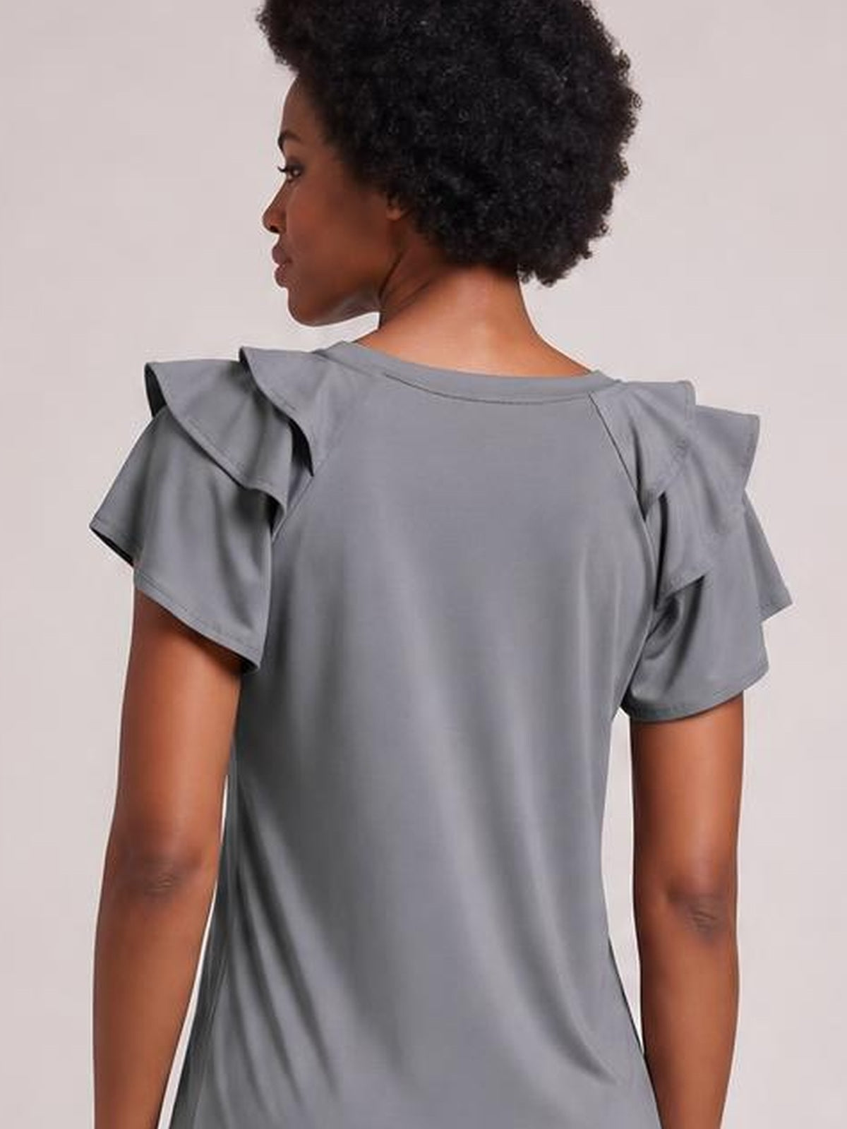 Model shown from the back in a solid gray layered flutter sleeve top with a round neck, short sleeves, and a relaxed regular-length silhouette.