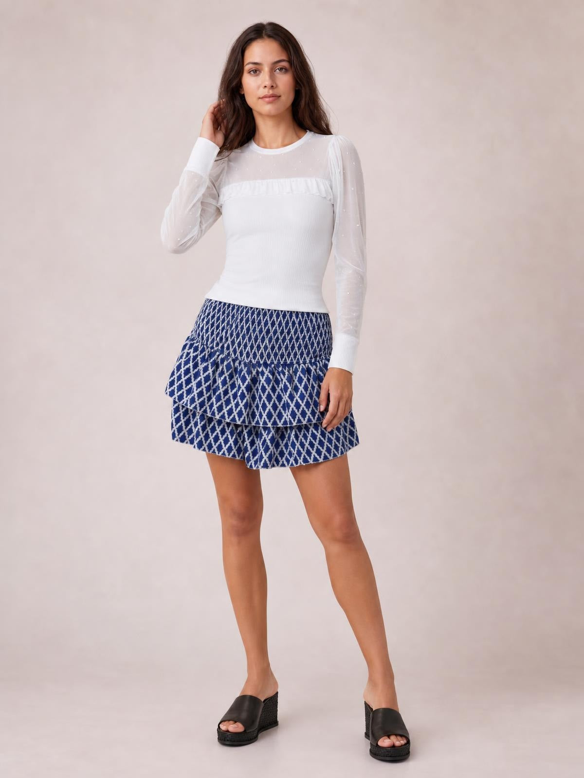 Model poses in a blue patterned Layered Mini Skirt with a smocked waistband, ruched texture, and tiered ruffled silhouette.