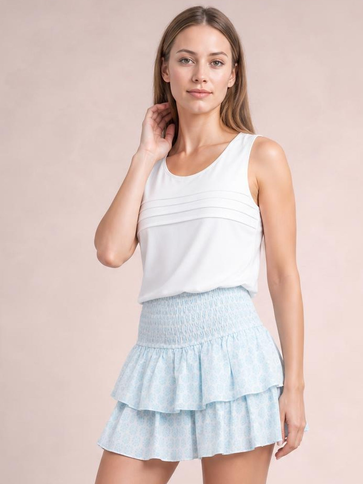 A model poses in a light blue layered mini skirt with a smocked waistband and two ruffled tiers creating a playful, flared silhouette.