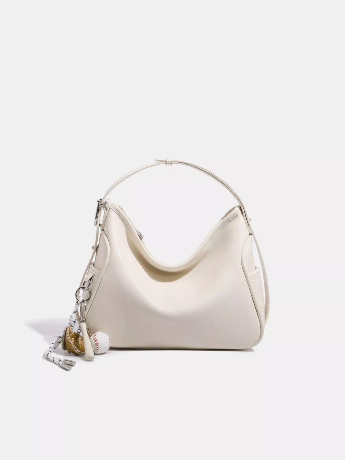 Cream medium slouchy shoulder bag in smooth PU leather, featuring a softly curved silhouette, gathered top, long shoulder strap, and decorative hanging charms.