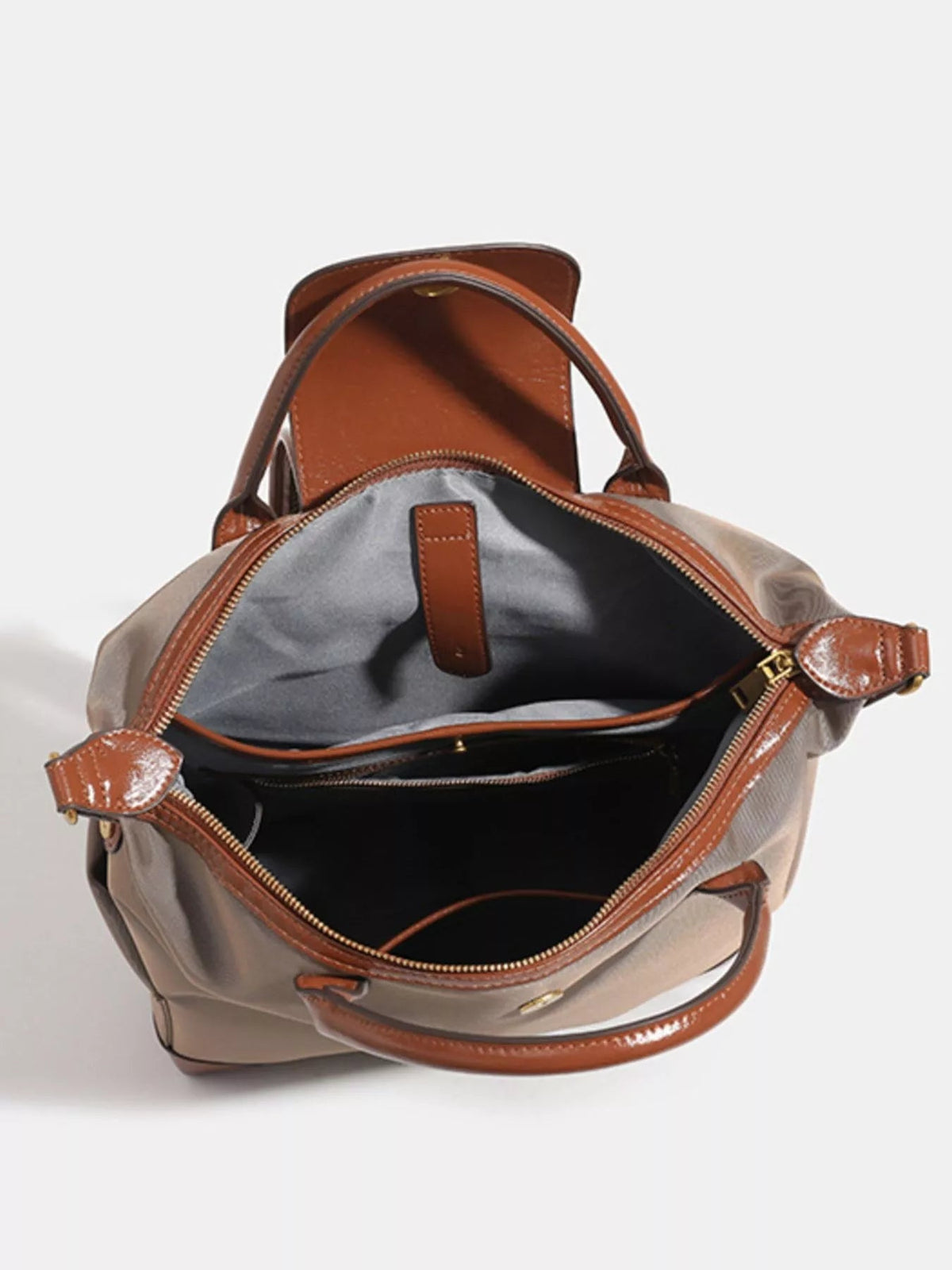 Open medium nylon backpack bag in taupe with brown faux-leather trim, dual handles, top zipper, and a spacious dark-lined interior.