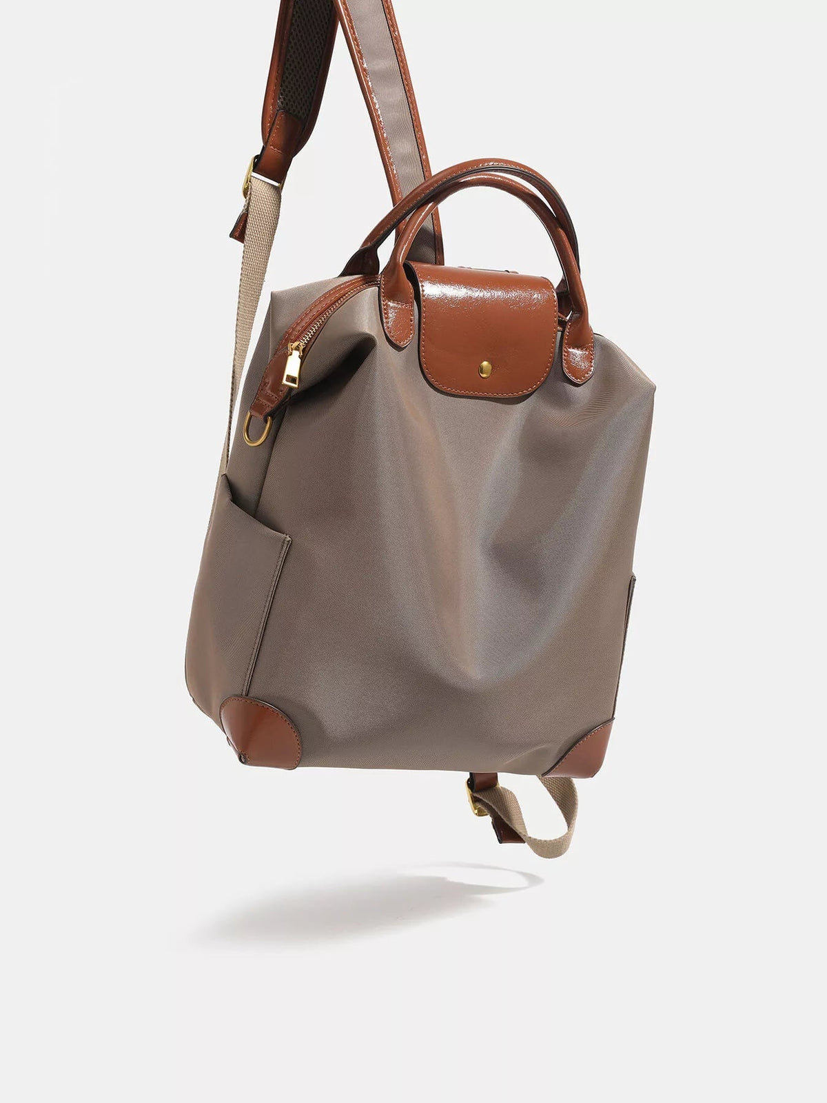 Medium taupe nylon backpack with glossy brown faux-leather trim, top handles, flap closure, zip detail, front pocket, and adjustable shoulder straps.