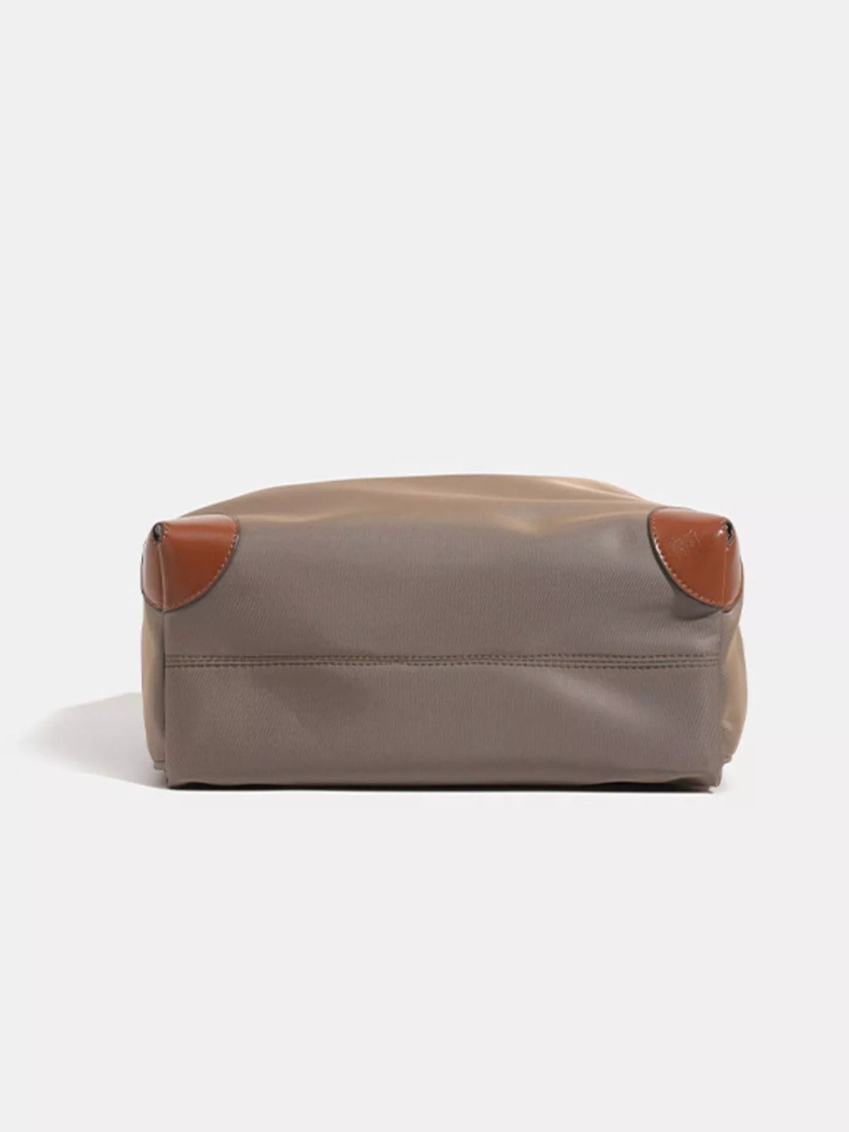 Medium taupe nylon backpack bag shown from below, with a structured rectangular silhouette, stitched paneling, and brown faux-leather corner trims.