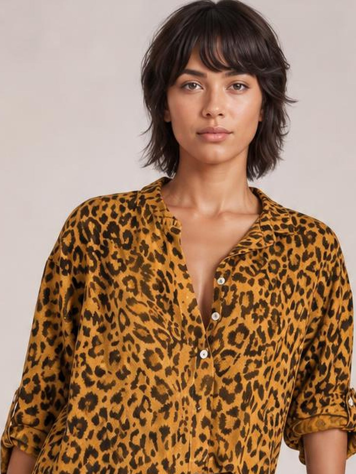 A model faces forward in an opaque leopard-print blouse with a notched neckline, button front, relaxed silhouette, and long sleeves rolled to the elbows.