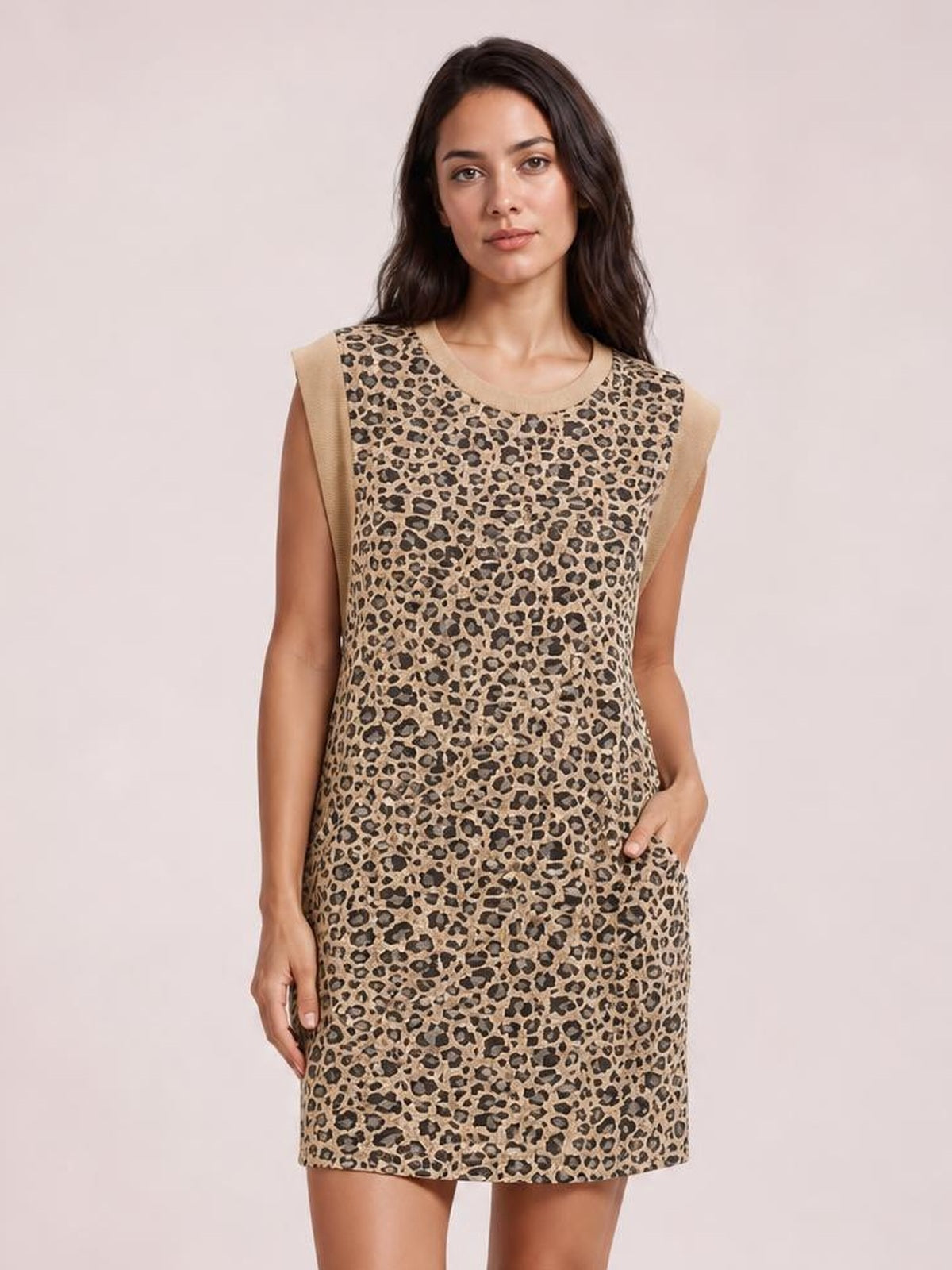 Model poses with one hand in a pocket, wearing a tan leopard-print mini dress with cap sleeves, a round neckline, and a straight silhouette.