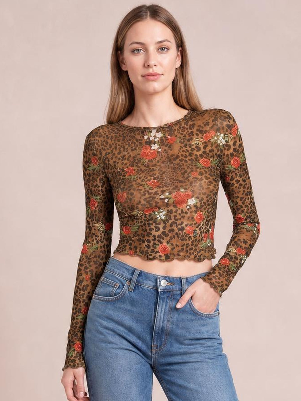 Model poses in a fitted sheer mesh T-shirt with a round neck, long sleeves, brown leopard floral print, and cropped raw-edge hem.