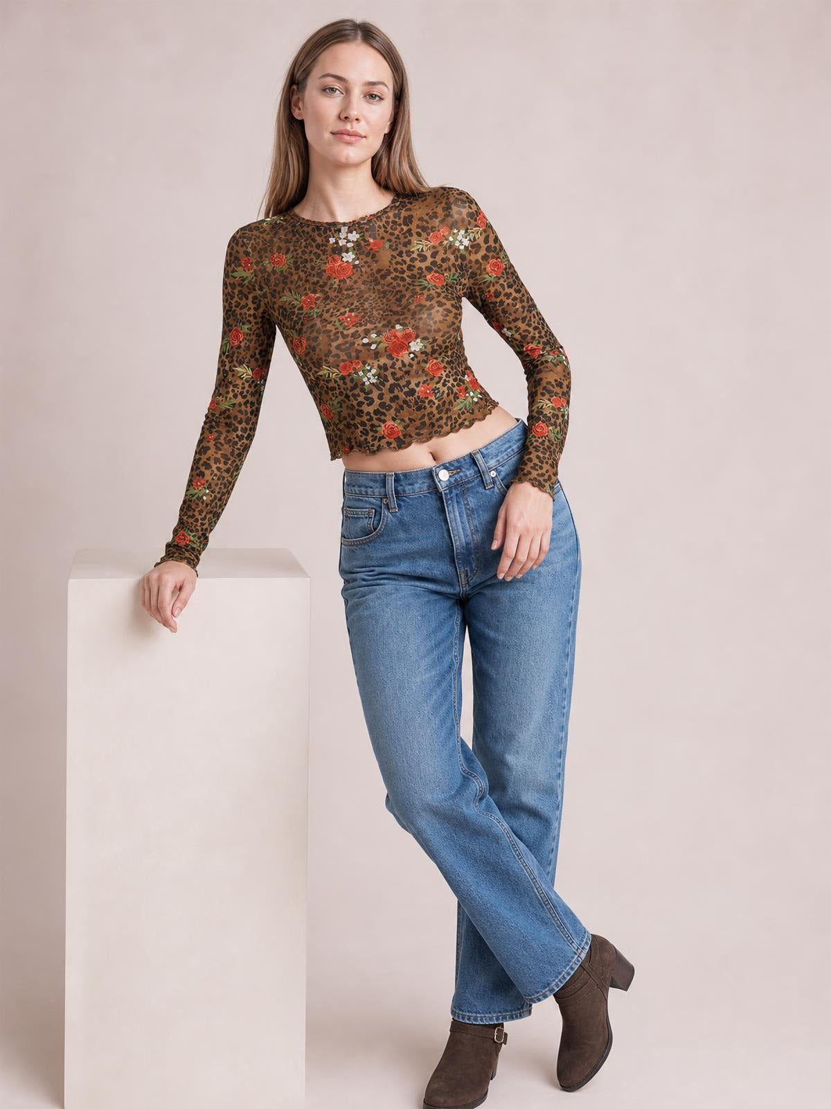 Model leans against a pedestal wearing a sheer brown leopard floral mesh T-shirt with a round neck, long sleeves, and a fitted cropped silhouette.