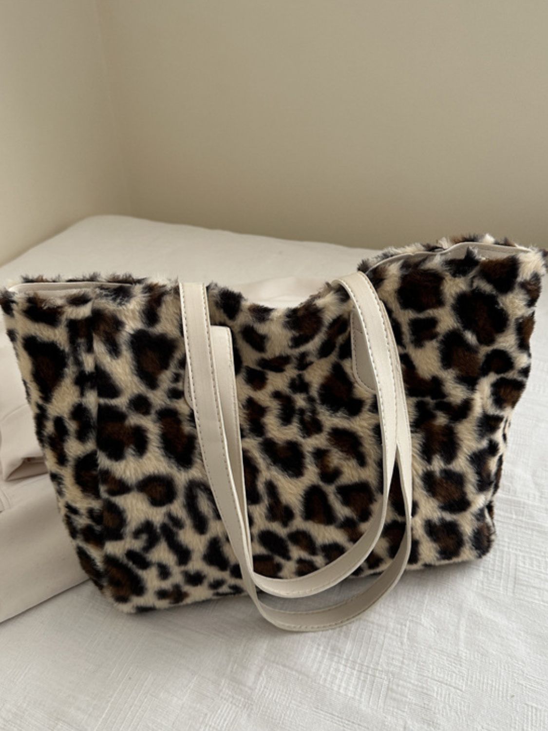 Leopard Fluff Tote Bag with a medium structured silhouette, plush spotted exterior, softly rounded edges, and contrasting cream PU leather double handles.