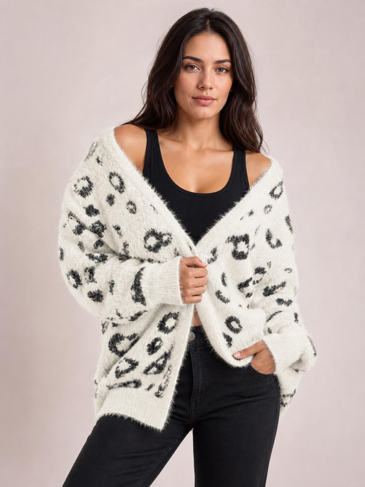 Model wears a white leopard-print open-front cardigan with long sleeves and pockets, holding the front in a relaxed pose over a black tank top.