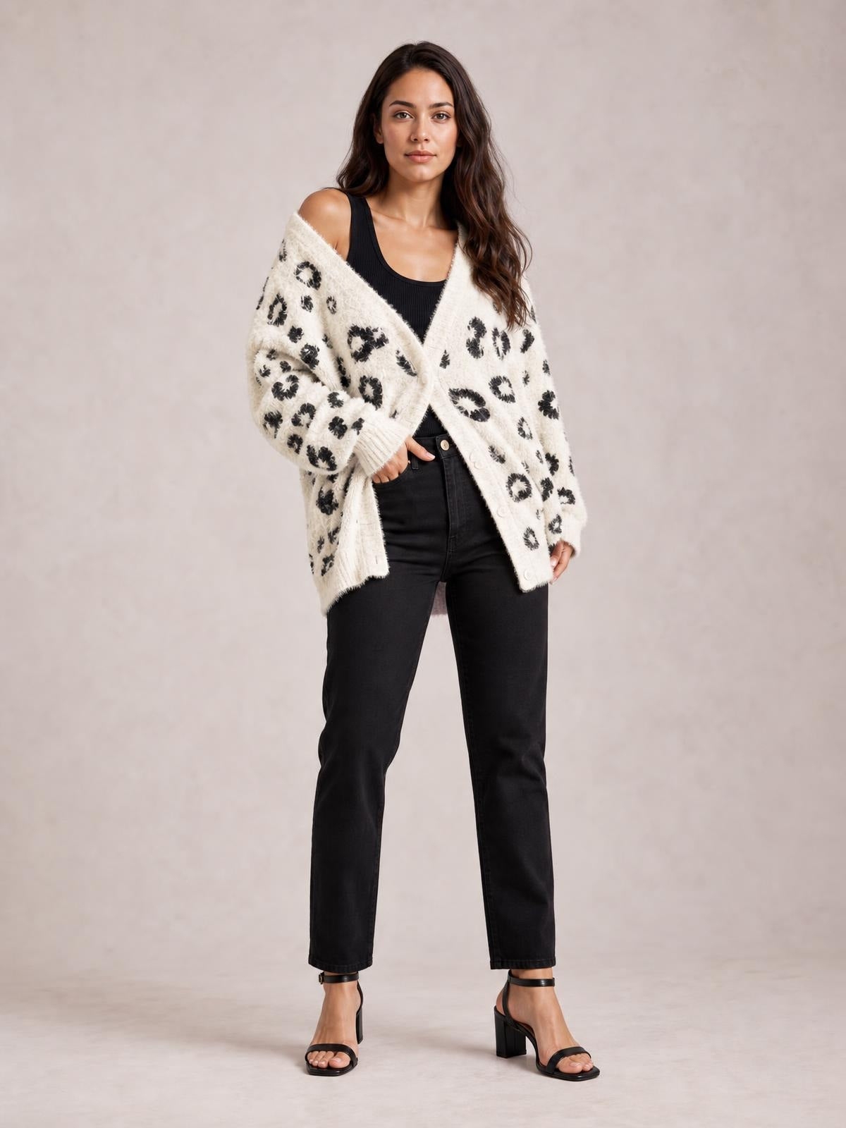 A model poses in a cream leopard-print open-front cardigan with long sleeves, a relaxed draped silhouette, and pockets over black jeans.