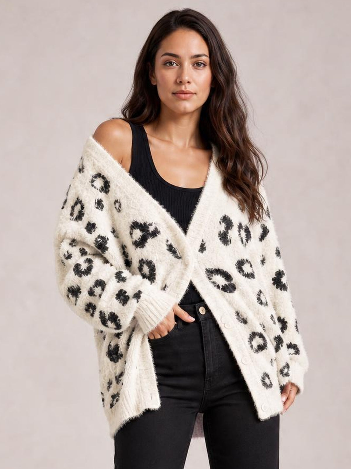 Model wears an ivory leopard-print open-front cardigan with long sleeves, ribbed cuffs, relaxed silhouette, and pockets over a black tank and jeans.