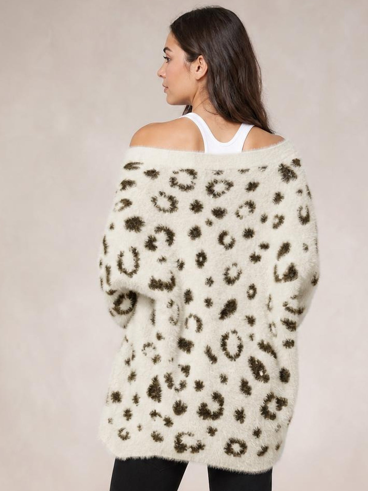 A model wears a cream leopard-print cardigan with a soft fuzzy texture, relaxed long silhouette, and dropped neckline while turning slightly to show the back.