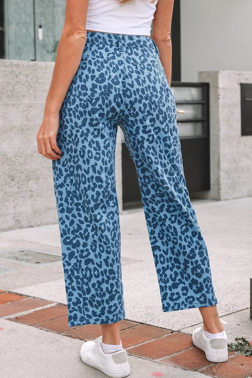Model wearing blue leopard print barrel leg jeans with a high waist, belt loops, pockets, and cropped wide-leg silhouette.