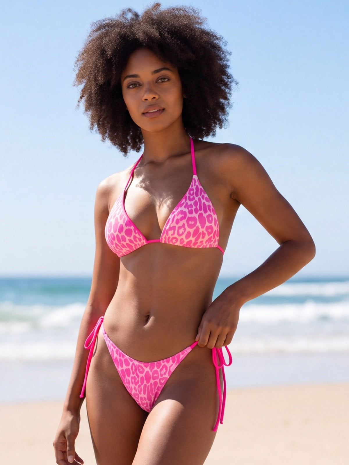 Model poses in a pink leopard print halter bikini set with triangle top, tie-side bottoms, and bright pink straps.