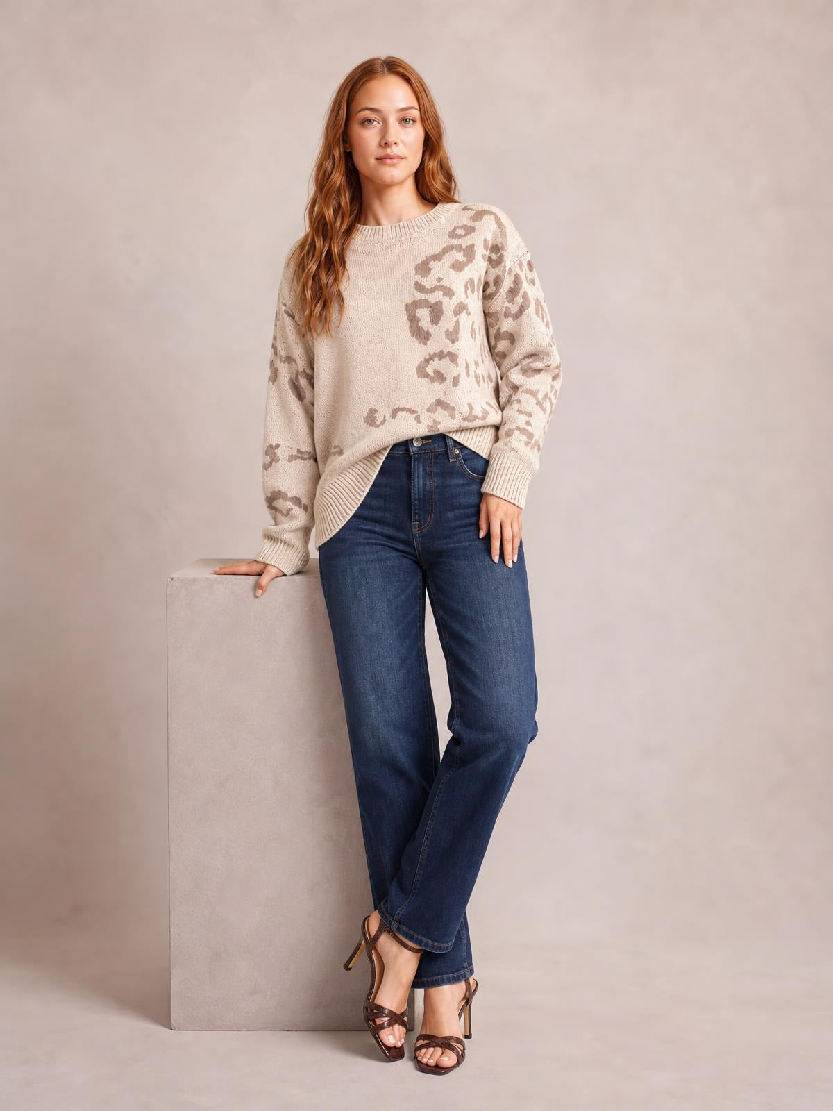 A model poses in a relaxed-fit ivory leopard-print sweater with a crew neckline, dropped shoulders, long sleeves, and ribbed cuffs and hem.
