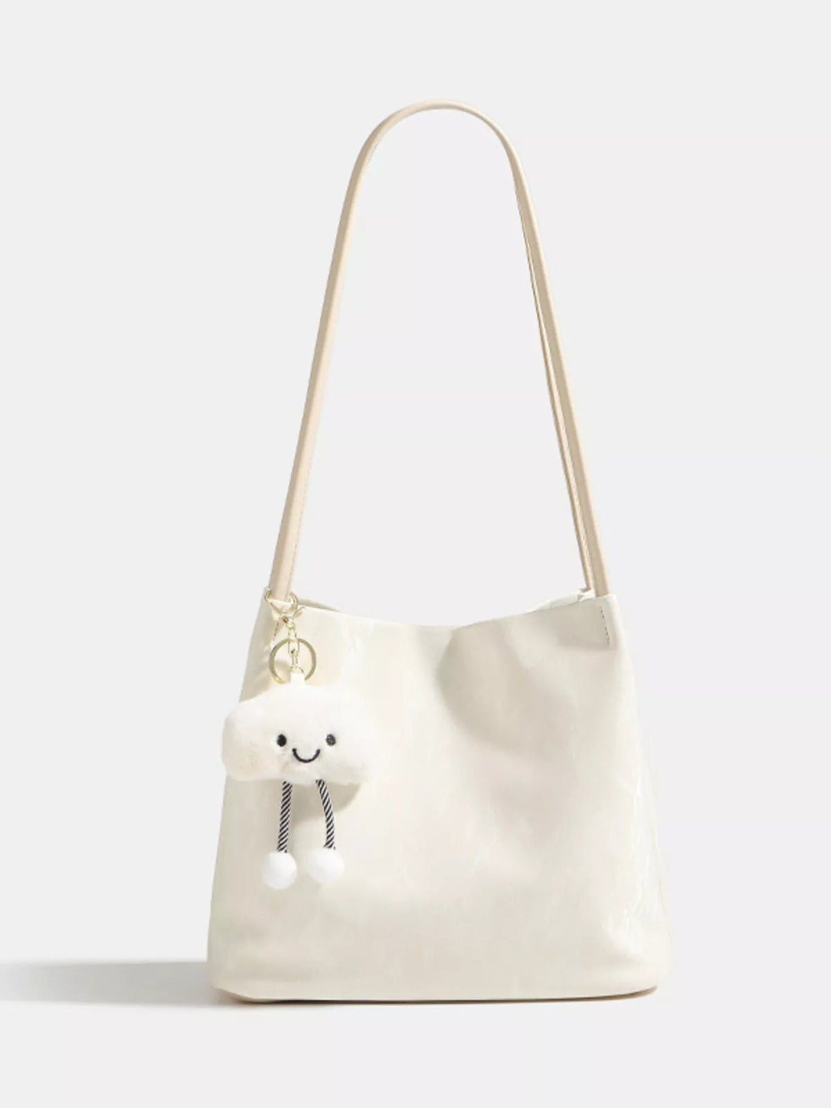 Cream medium PU leather shoulder bag with a long strap, softly structured silhouette, smooth construction, and a playful cloud charm with dangling pom-poms.