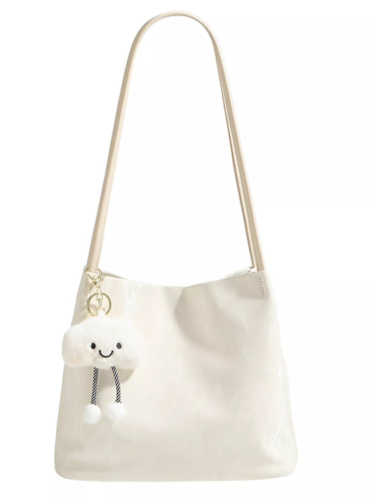 A medium ivory PU leather shoulder bag with a long strap, softly structured silhouette, glossy finish, and a playful plush cloud charm with dangling pom-poms.